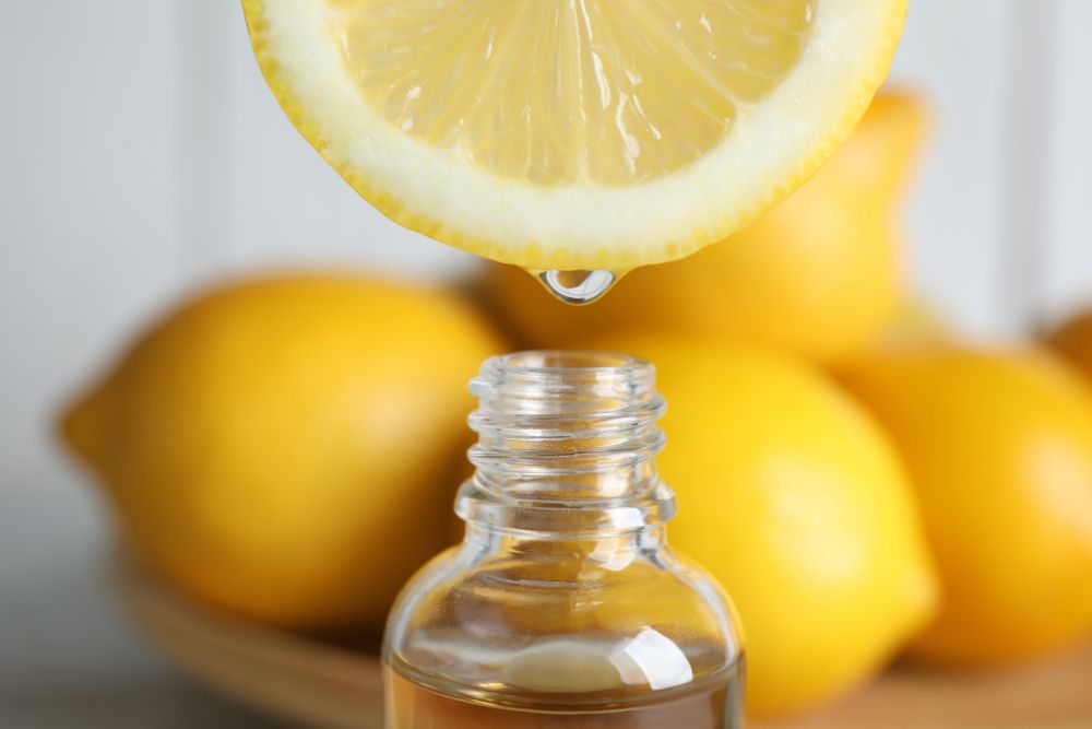 Zitronensaft tropft in eine Flasche – Zitrusöle können photosensibilisierend wirken.