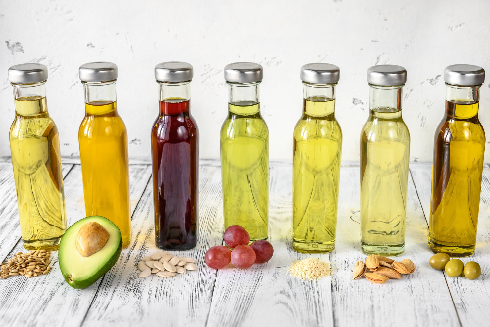 Verschiedene Arten natürlicher Trägeröle in Fläschchen – Avocado, Traubenkerne, Oliven und andere Rohstoffe