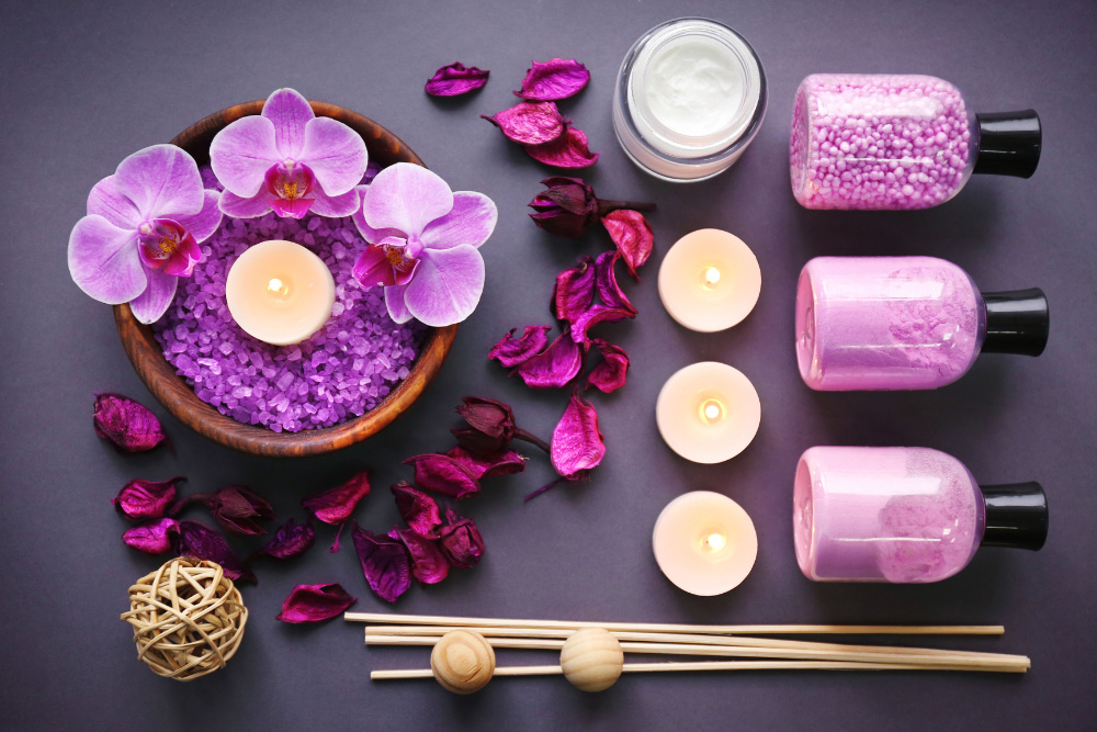 Aromatherapeutische Komposition mit lila Orchideen, brennenden Kerzen, Salz und ätherischen Ölen